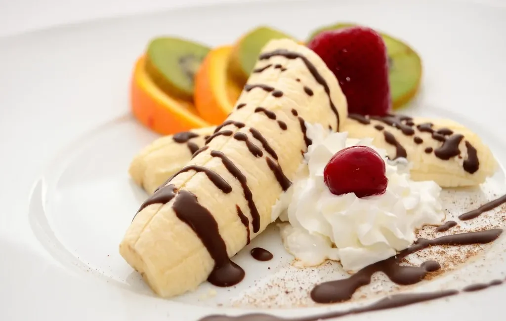 Banana split with chocolate sauce, whipped cream and fruit
