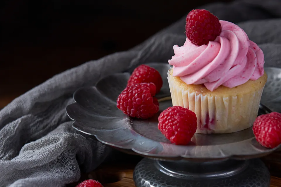 Cupcake with pink frosting and raspberries