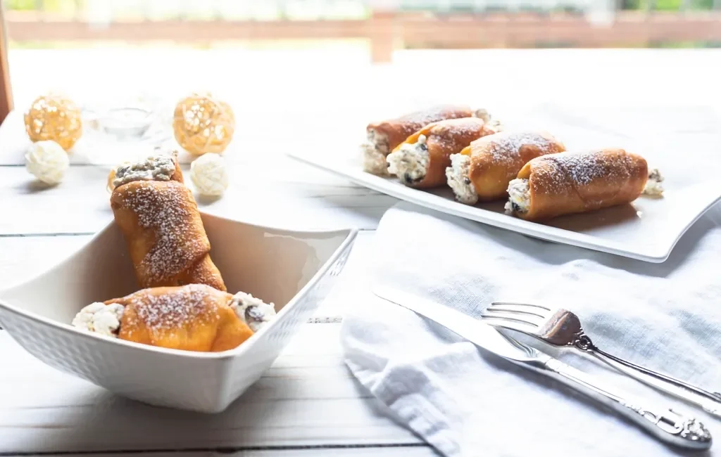 Cannoli dusted with powdered sugar on white plates