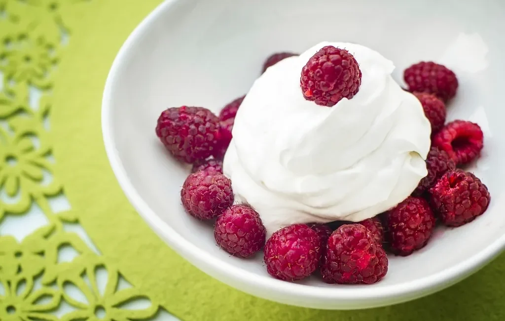 Bowl of whipped cream with raspberries