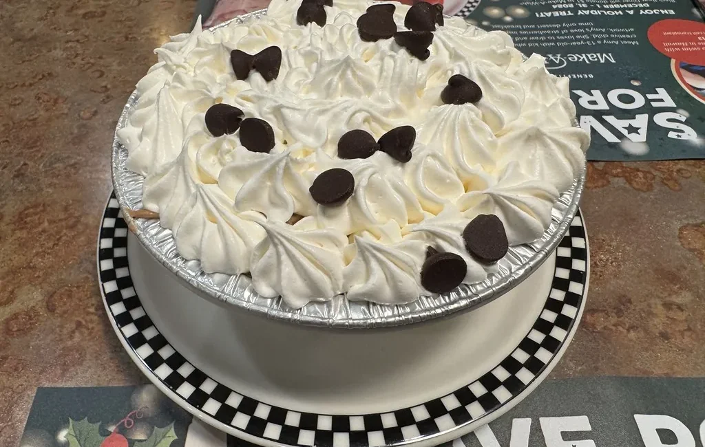 Pie topped with whipped cream rosettes and chocolate pieces