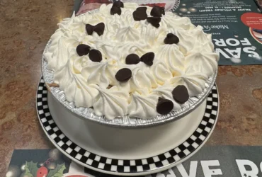 Pie topped with whipped cream rosettes and chocolate pieces