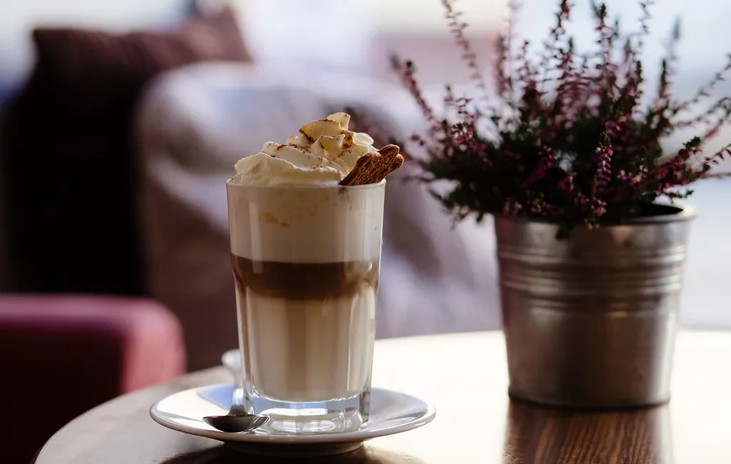 Layered latte in a glass topped with whipped cream
