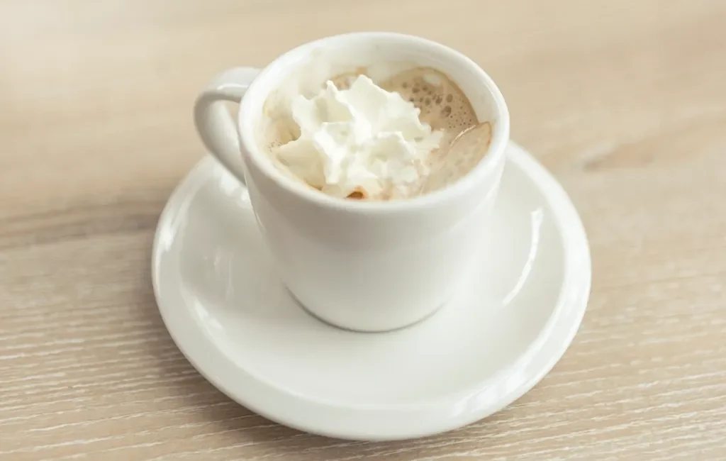 Espresso topped with whipped cream in a white mug