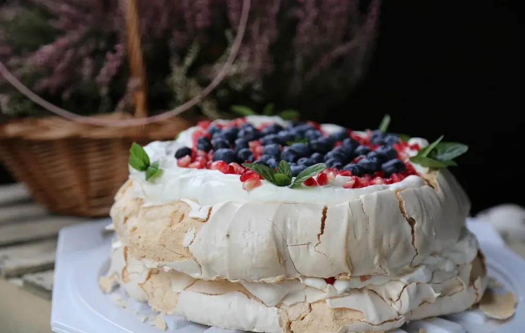 Pavlova topped with cream and mixed berries